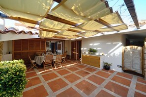 A covered patio area with a table set for dining, wooden furniture, and potted plants. - Villa Portobello 10+2, Emma Villas (Portobello)