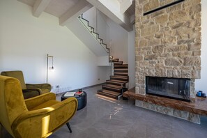 Ein modernes Wohnzimmer mit Kamin aus Stein, einer Treppe und einem gelben Sessel.
