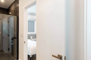 Ein Hotelzimmer mit Bett, Nachttisch, Wand-Klimaanlage und einer Tür zu einem weiteren Raum.