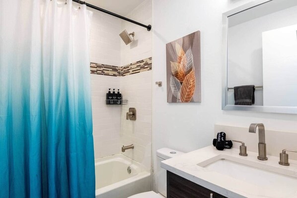 A bathroom with a shower, a bathtub, a sink with a mirror, and a towel rack.