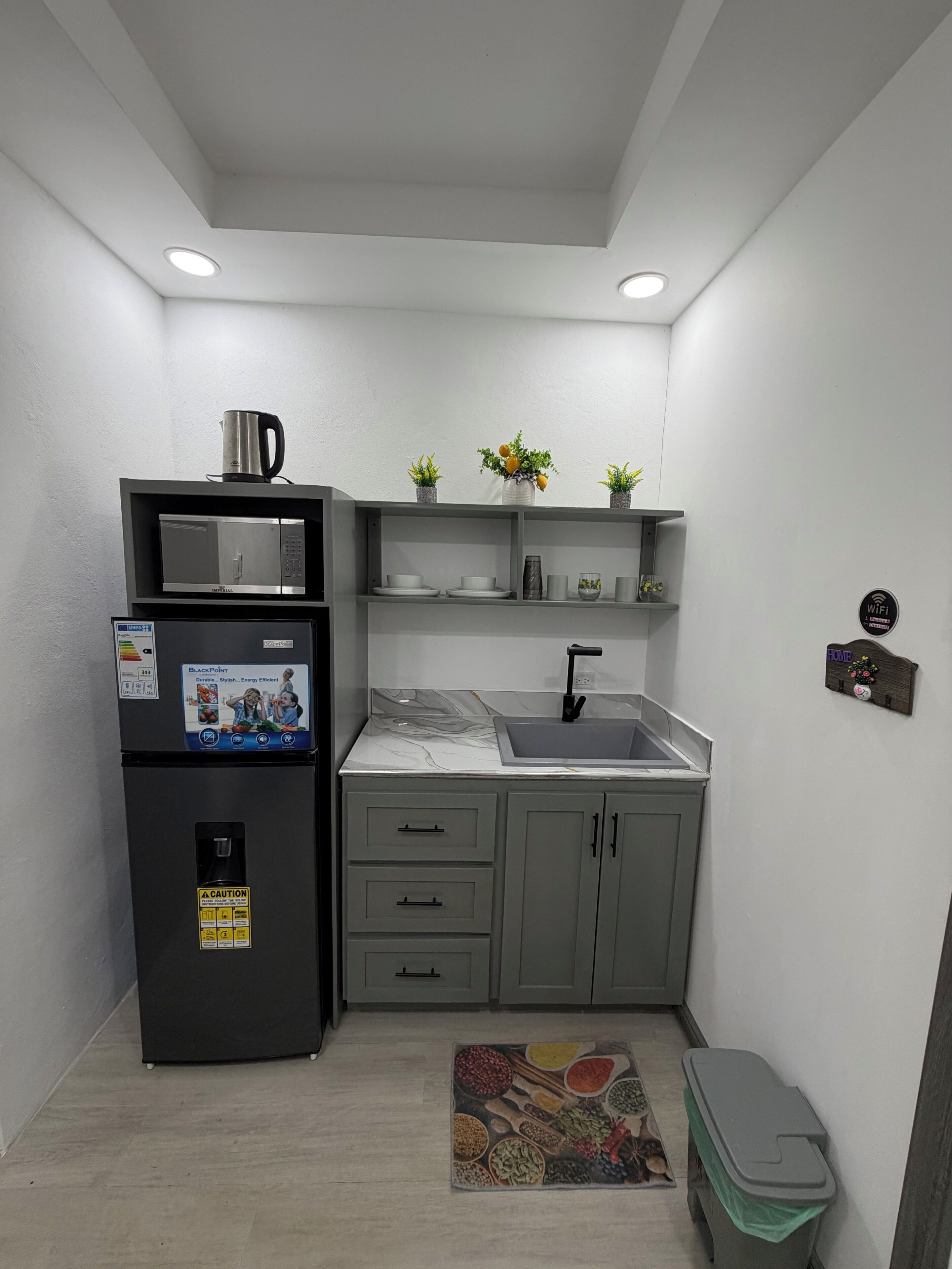 Eine kleine Küche mit Kühlschrank, Mikrowelle, Spüle und einer Arbeitsfläche.