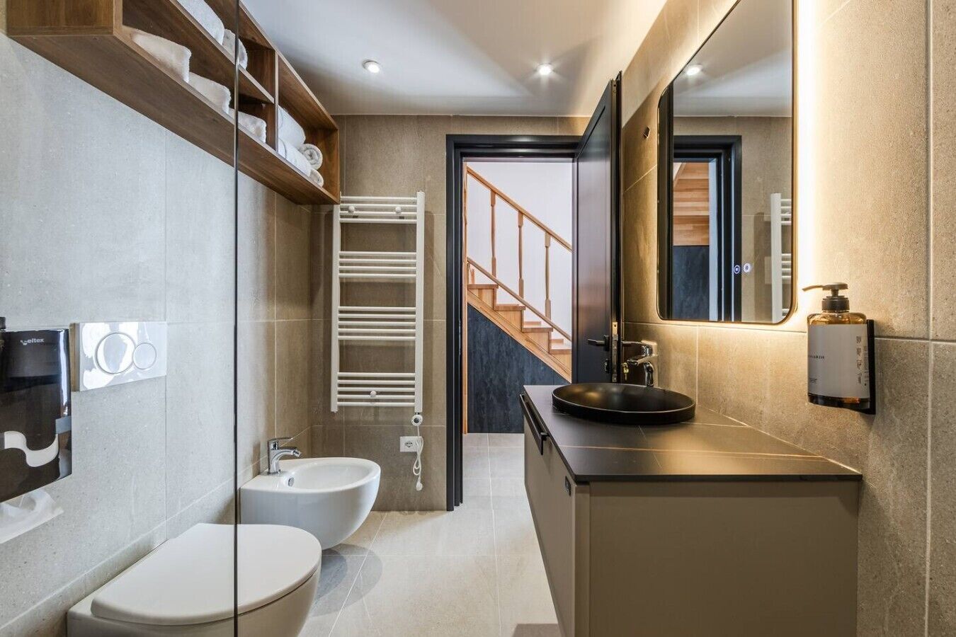 A modern bathroom with a bidet, toilet, and a sink with a mirror.