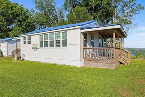 A single-story house with a porch, a covered deck, and a view of the water.