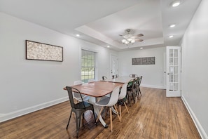 A dining area with a wooden table, chairs, and a ceiling fan.
