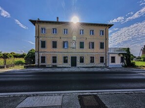 Un edificio de dos pisos con una entrada central, varias ventanas y un cielo despejado.