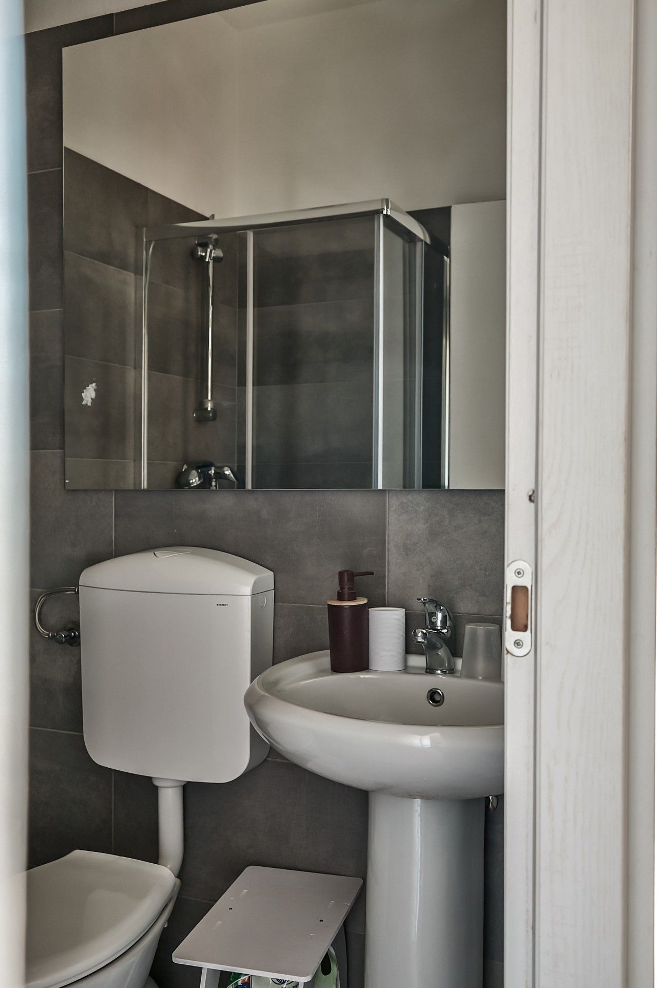 A compact bathroom with a toilet, sink, and shower.