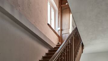 Eine Treppe mit Holzstufen und einem Metallgeländer, die zu einem Raum mit Fenster und Tür führt.