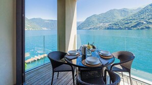 Ein Balkon mit Esstisch, Blick auf einen See mit Bergen im Hintergrund.