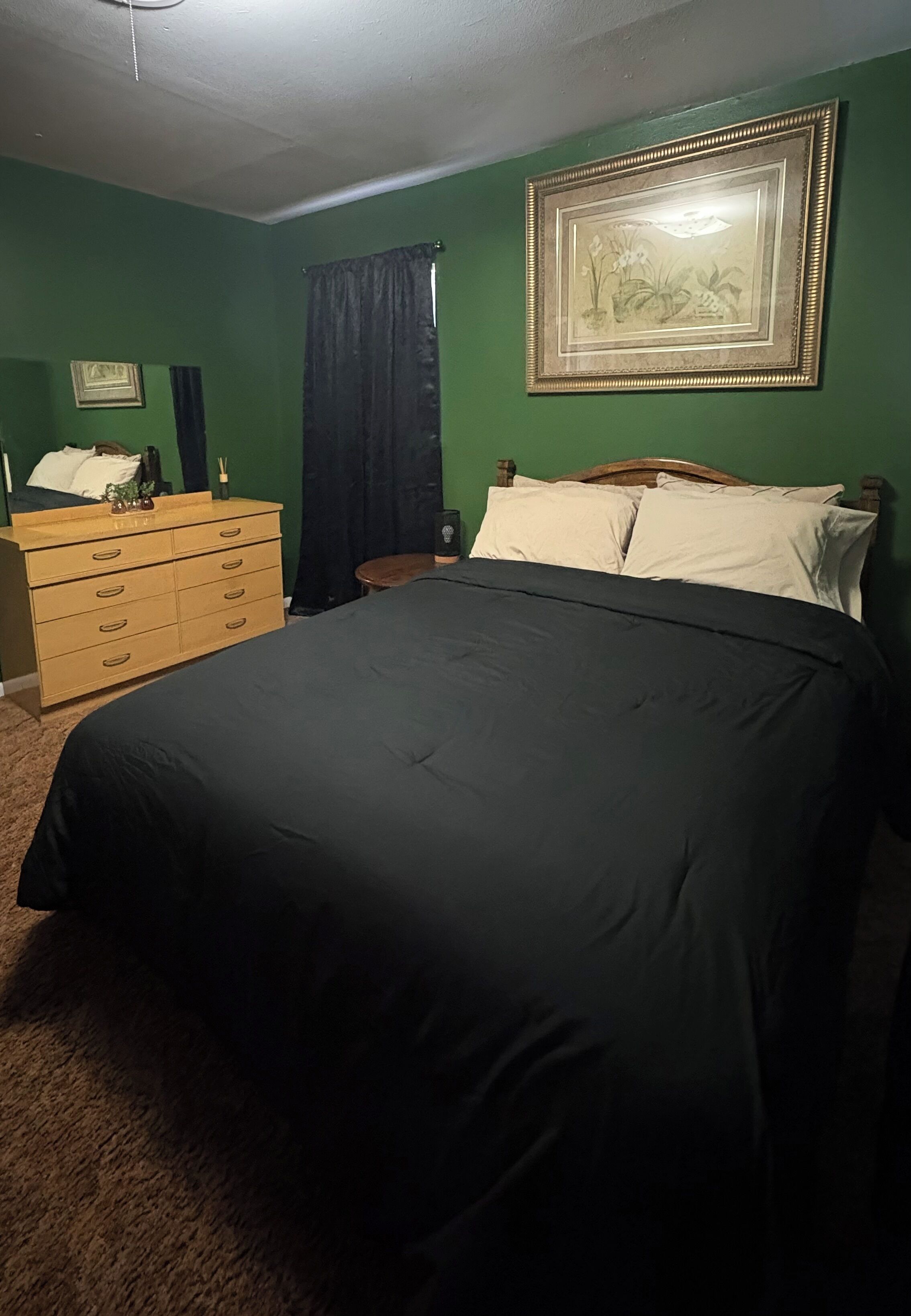 Un dormitorio con cama, cómoda y un cuadro en la pared.