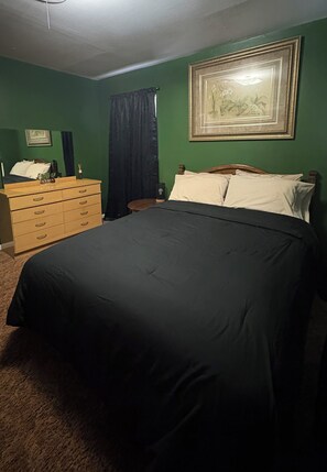 A bedroom with a bed, dresser, and a framed picture on the wall.