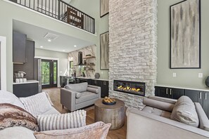 A spacious living area with a fireplace, high ceilings, and modern furnishings. - Experience the perfect Pigeon Forge getaway at The Suite Life, a thoughtfully de (Pigeon forge)