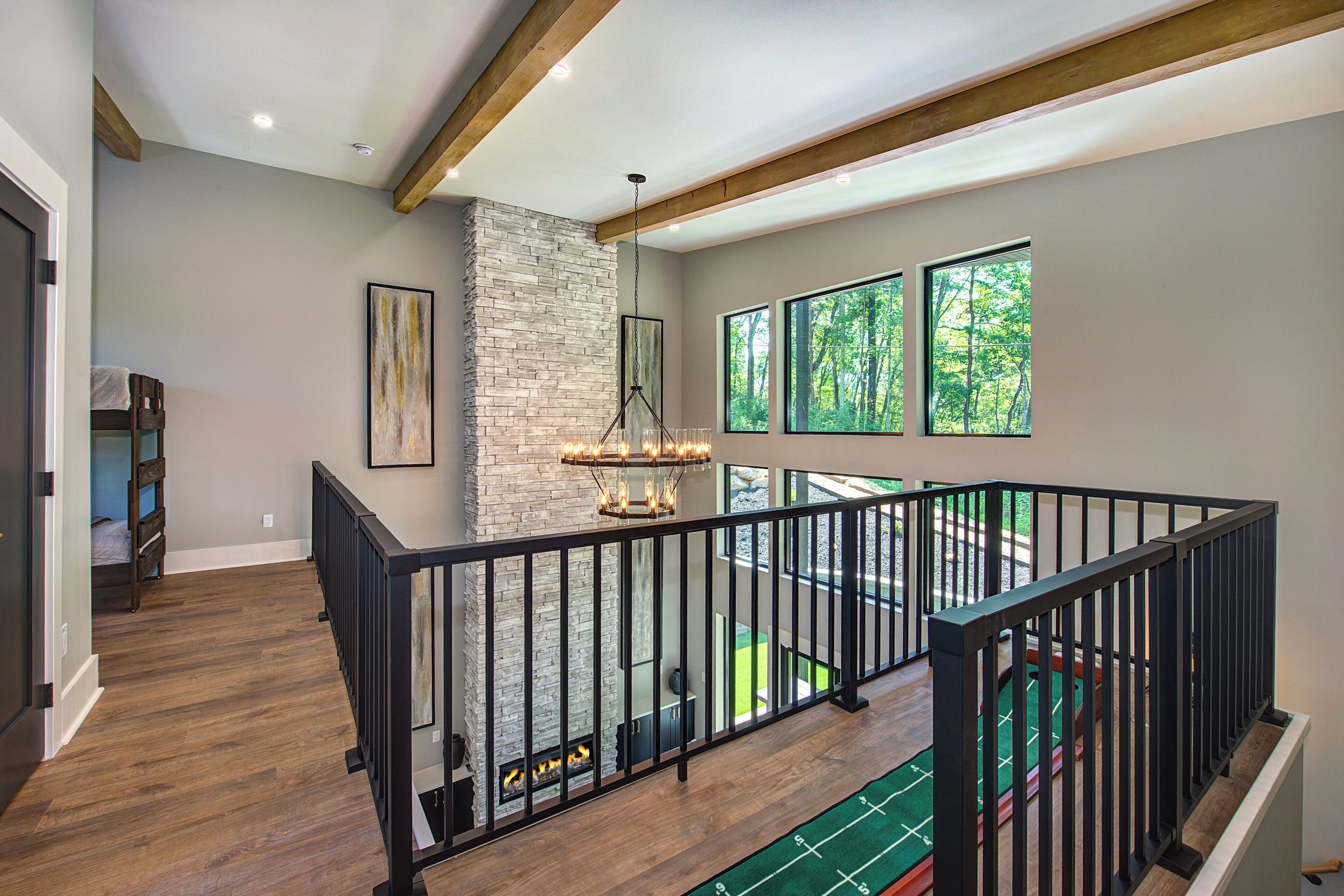 A spacious interior with a stone fireplace, large windows, and a wooden staircase.
