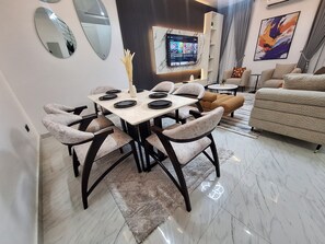A modern dining area with a marble floor, a dining table set for six, and a sofa in the background. - Lovely 3-bedroom house with 24/7 power supply, security, gym and pool in Lekki (Lekki)