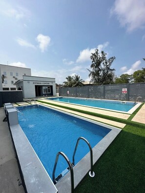 A fitness center with a pool area, including a main pool and a smaller pool, surrounded by a fence and greenery. - Lovely 3-bedroom house with 24/7 power supply, security, gym and pool in Lekki (Lekki)