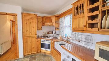 A compact kitchen with wooden cabinets, a washing machine, a microwave, and a sink.