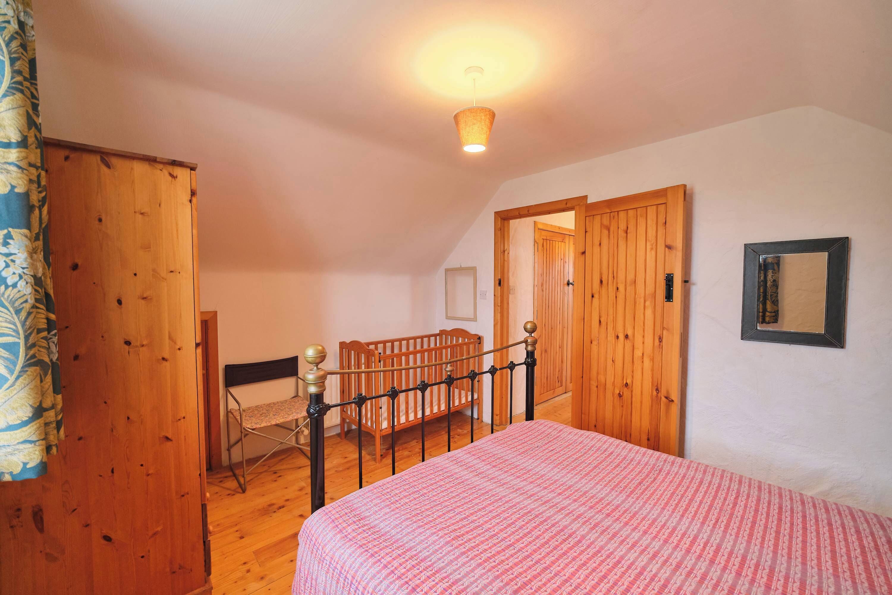 Une chambre à coucher avec un lit, des meubles en bois et une porte donnant sur une autre pièce.