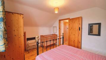 Une chambre à coucher avec un lit, des meubles en bois et une porte donnant sur une autre pièce.