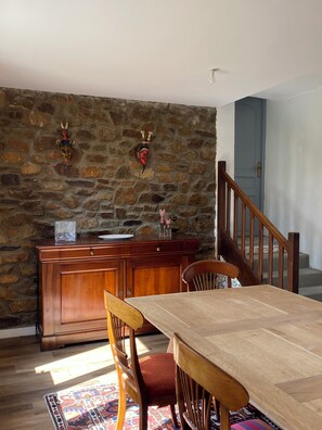 Ein Essbereich mit Holztisch und -stühlen, einer Steinwand mit Masken und einer Treppe.