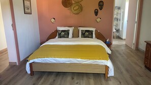 A bedroom with a wooden bed, a yellow throw blanket, and decorative wall art. - Charming Family House 10 min from Mont-Saint-Michel – Sleeps 10 (Servon)