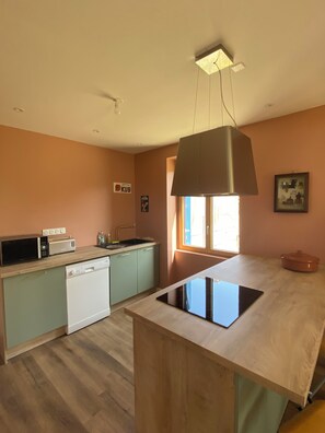 Una cocina moderna con una isla central, lavavajillas empotrado, microondas y tostadora.