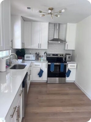 Una cocina moderna con armarios blancos, electrodomésticos de acero inoxidable y piso de madera.
