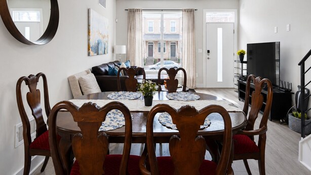 Un coin repas avec une table ronde, des chaises et un miroir au mur.