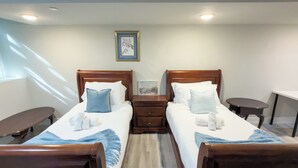 Une chambre d’hôtel avec deux lits, une petite table, une table de chevet et un tableau au mur.