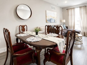 A dining area with a round table, chairs, and a mirror on the wall.