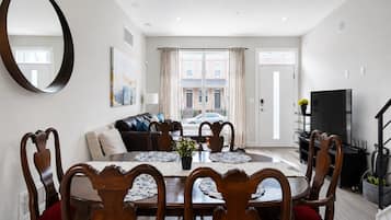 A dining area with a round table, chairs, and a large mirror on the wall.