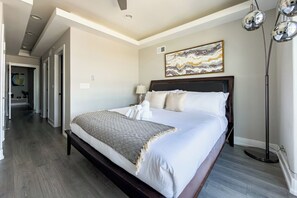 Habitación de hotel con una cama grande, una lámpara de pie y un cuadro en la pared.