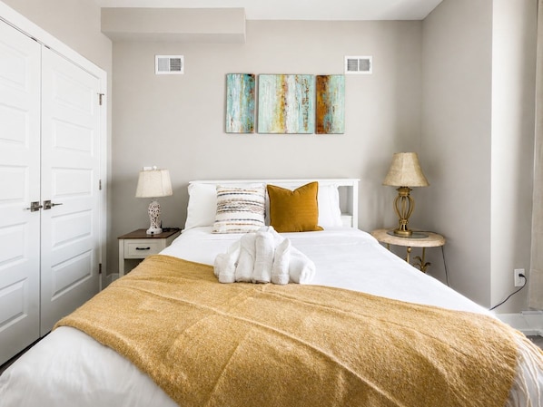A hotel room with a bed, a nightstand, a lamp, and a set of towels.