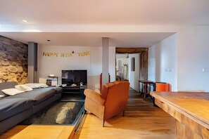 A modern living room with a sofa, a wooden coffee table, a TV, and a 'Happy New Year' banner. - A Varanda do Tempo Apartment: Archaeology, History, Terrace & Wi-Fi in Central Coimbra (Coimbra)