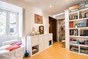 A room with a bed, a white dresser with drawers, a bookshelf, and a window with a view. - A Varanda do Tempo Apartment: Archaeology, History, Terrace & Wi-Fi in Central Coimbra (Coimbra)