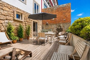 A wooden deck with outdoor furniture, a fire pit, and potted plants. - A Varanda do Tempo Apartment: Archaeology, History, Terrace & Wi-Fi in Central Coimbra (Coimbra)