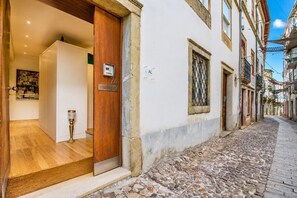 A narrow cobblestone street with a building entrance featuring a wooden door with a number plate. - A Varanda do Tempo Apartment: Archaeology, History, Terrace & Wi-Fi in Central Coimbra (Coimbra)