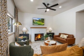 Ein Wohnzimmer mit Kamin, Deckenventilator und einem Bild an der Wand.