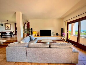 Una sala moderna con un sofá modular, un televisor de pantalla plana y un balcón con vistas.