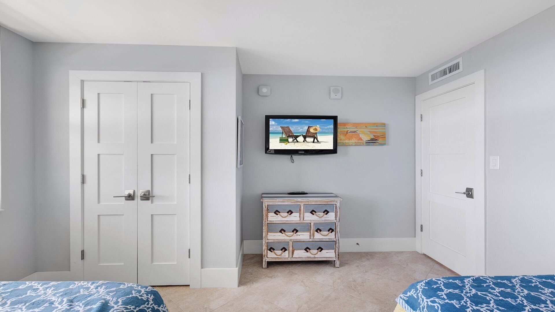 Ein Schlafzimmer mit zwei Betten, einem an der Wand befestigten Fernseher und einer Kommode.