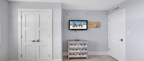 Ein Schlafzimmer mit zwei Betten, einem an der Wand befestigten Fernseher und einer Kommode.