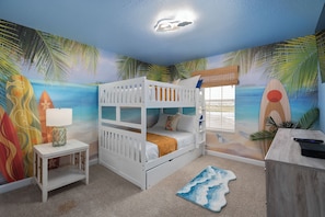 A bunk bed room with a beach mural, a small table with a lamp, and a desk with a keyboard. - Lakeview Pool Townhome in Storey Lake Resort • Lazy River • 8 Miles to Disney (Kissimmee)