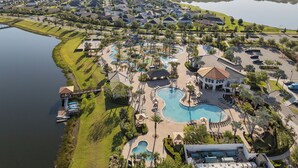 Ein Resort mit mehreren Schwimmbecken, darunter ein großes zentrales Becken, und Blick auf einen See.