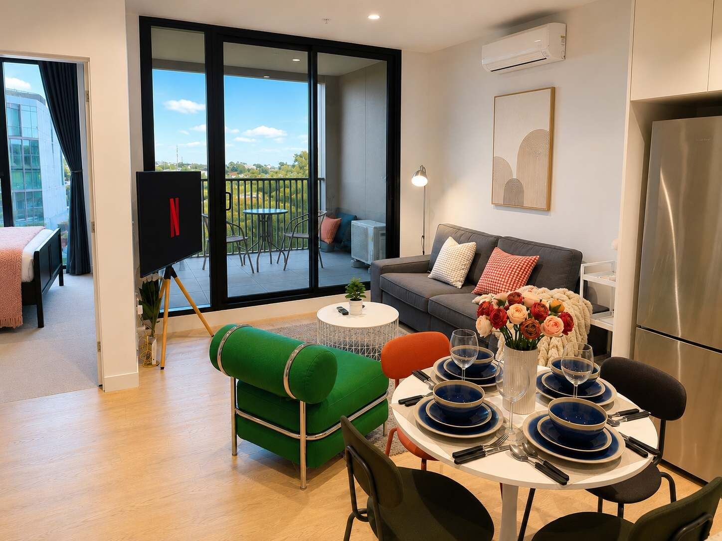 Ein modernes Wohnzimmer mit Essbereich, einer Couch, einem Fernseher und einem Balkon mit Blick.