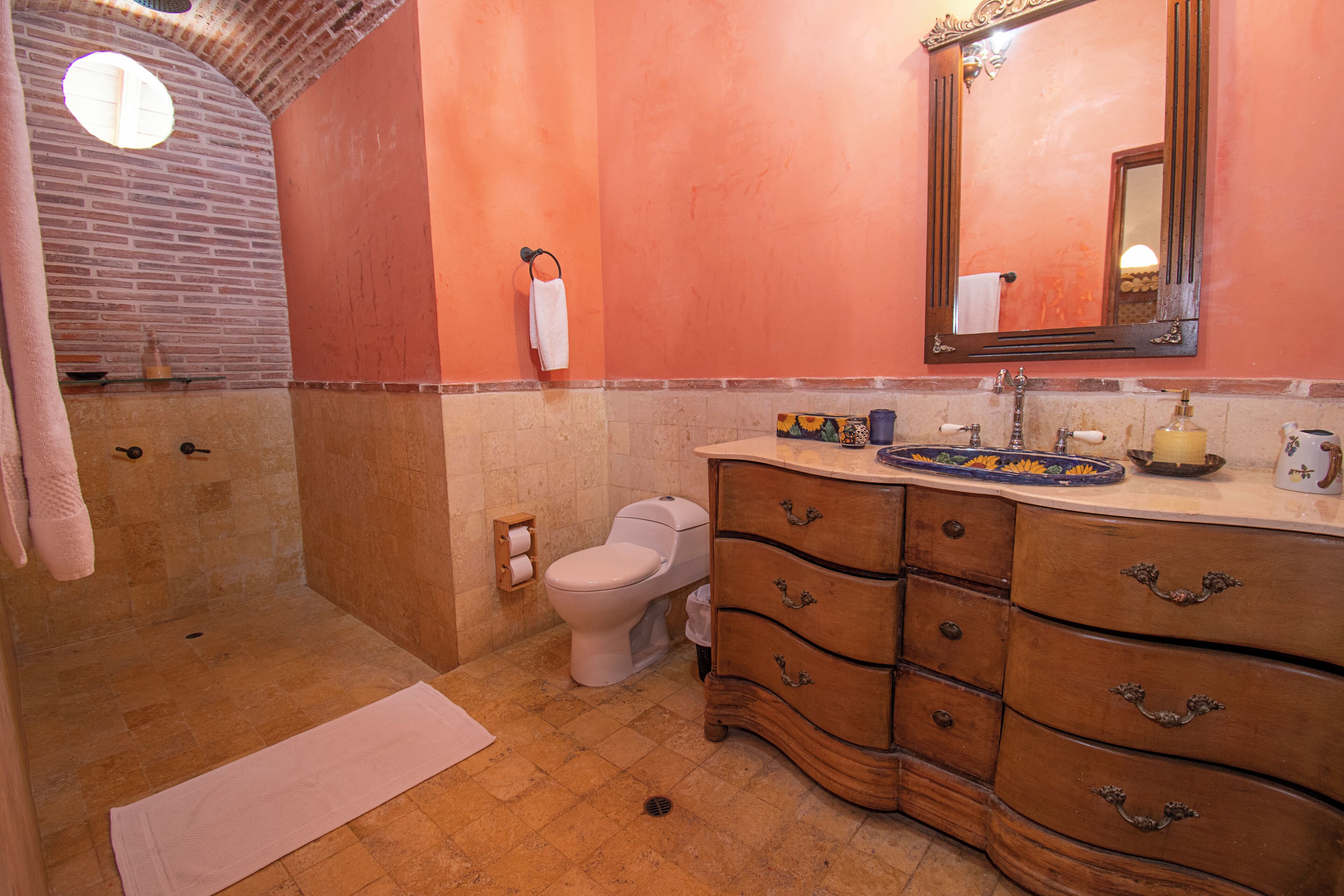 A bathroom with a shower, toilet, vanity with drawers, and a mirror.