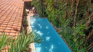 A swimming pool with a tiled roof, surrounded by greenery and plants. - Casa Mejia (Cartagena de Indias)