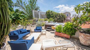 An outdoor seating area with blue sofas, white tables, and potted plants. - Casa Mejia (Cartagena de Indias)