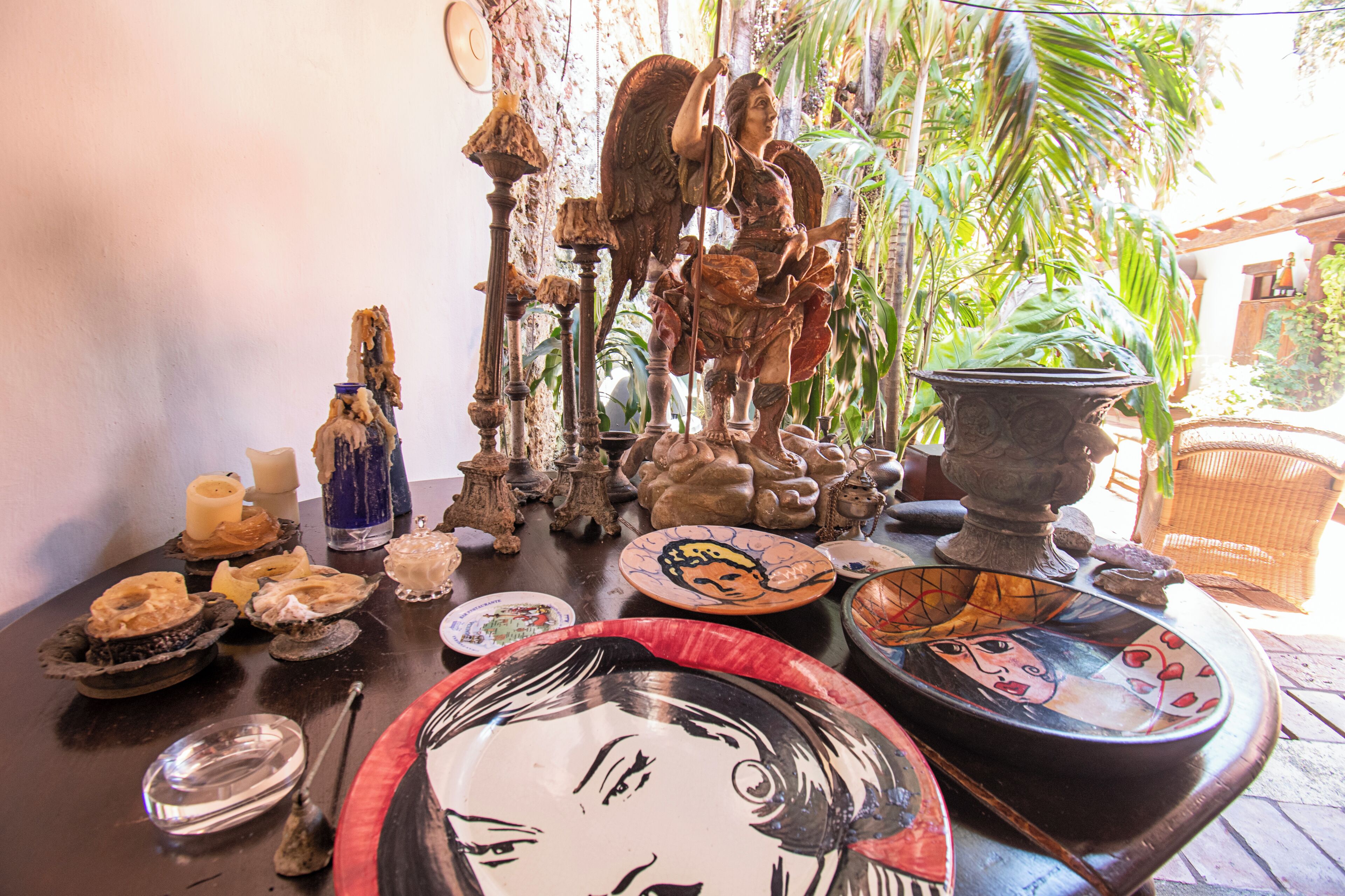 A table with various decorative items including a statue, pottery, and plates.