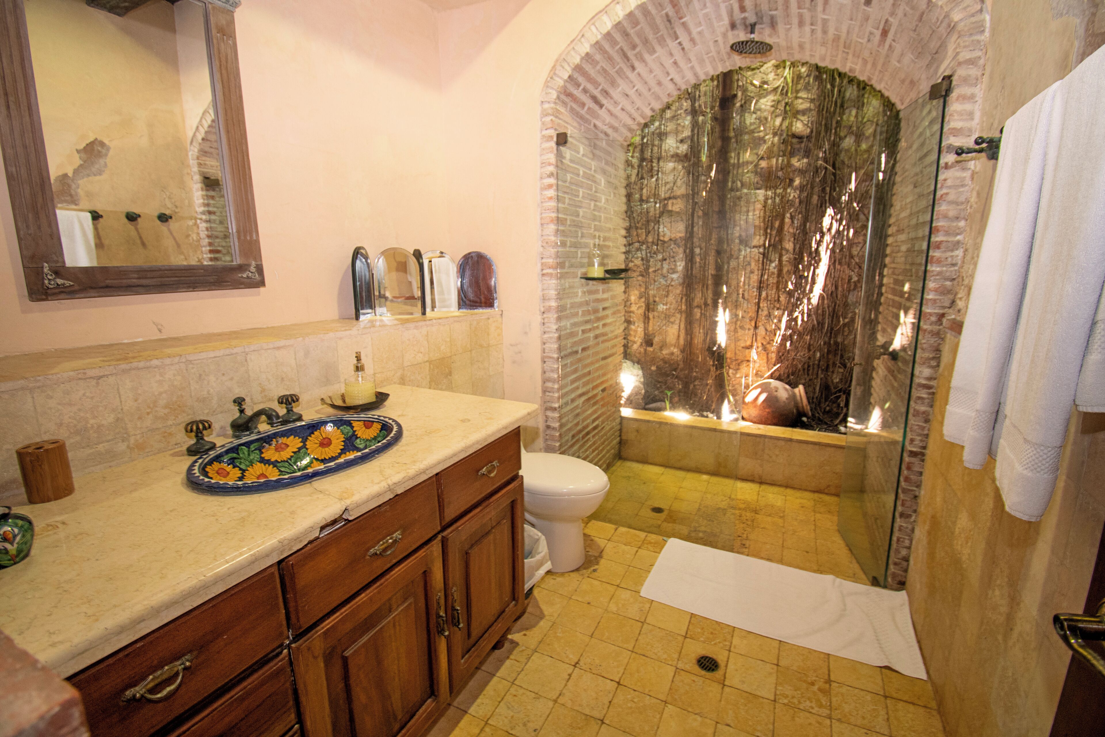 Une salle de bain équipée d’un lavabo, d’un miroir et d’une zone de douche délimitée par une paroi en verre.