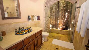 A bathroom with a sink, mirror, and a shower area with a glass enclosure.
