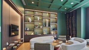 A modern living room with a sectional sofa, a coffee table, and a TV mounted on the wall. - Downtown Studio with Pool, Gym & Movie Theater (Miami)