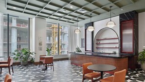 A modern interior with a geometric patterned floor, a bar area with shelves, and seating arrangements. - Downtown Studio with Pool, Gym & Movie Theater (Miami)